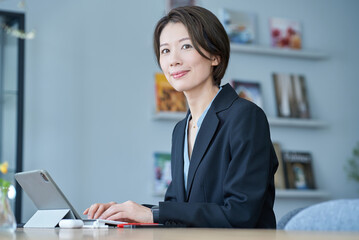 タブレットPCの前に座るスーツ姿の女性