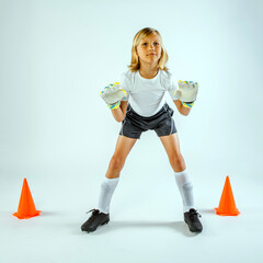 Young male soccer goalie standing between two cones with gloved hands raised ready to protect the...