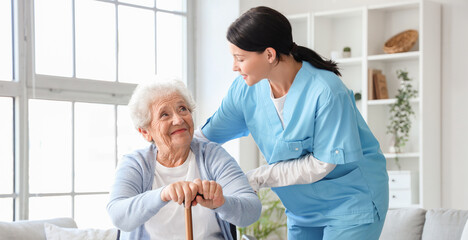 Senior woman in wheelchair with stick and nurse at home