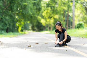 Healthy young female runner stretches her legs before running in the park. Woman exercising for...