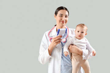 Female pediatrician with infrared thermometer and little baby on light background