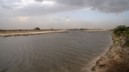 Panorama view of the river before the storm. View of the shoreline and flowing water under a...