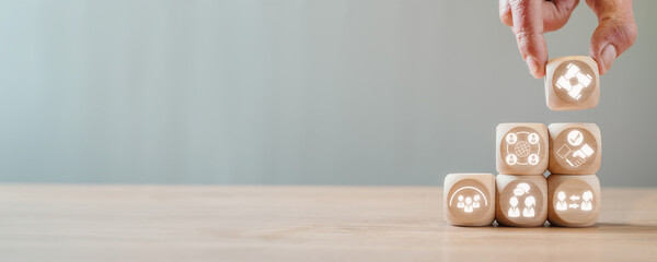 Social capital concept, Hand holding wooden block on desk with participation, network, trust, belonging, engagement and reciprocity icon on virtual screen