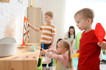Little children with nursery teacher playing in kindergarten