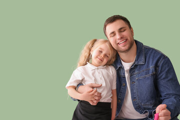 Happy father with his cute little schoolgirl on green background