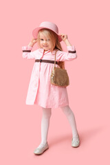 Cute little girl with stylish golden purse on pink background