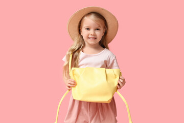 Cute little girl with stylish yellow bag on pink background