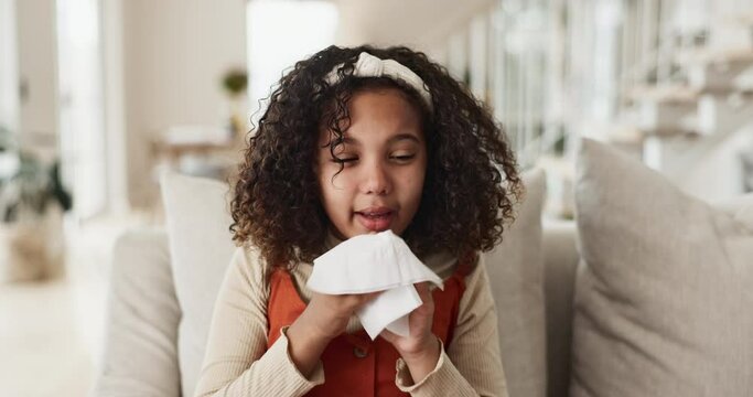 Sick, little girl and blowing nose with tissue on sofa for fever, flu or symptoms in living room at home. Young female person, child or kid with cold, illness or allegies on lounge couch at house