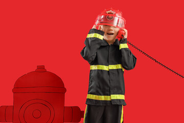 Cute little firefighter with paper hydrant talking by telephone on red background