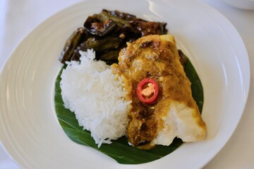 Main dish of Portuguese-styled grilled fish with steamed rice, stir-fried eggplant and okra served on a banana leaf on a business class flight from Sydney to Kuala Lumpur