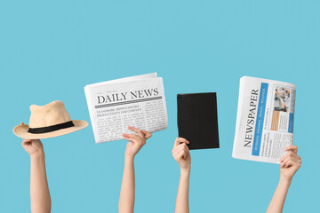 Female hands with newspapers, hat and notebook on color background