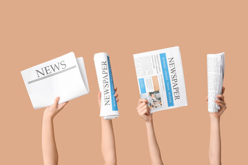 Women holding different newspapers against color background