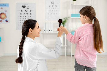 Female ophthalmologist with occluder and little girl in clinic