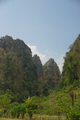 The mountains are covered in lush green trees and the sky is clear and blue