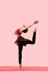 Naklejka premium Little girl doing gymnastics on pink background
