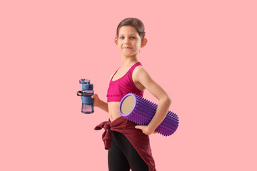 Little gymnast with water bottle and foam roller on pink background