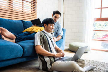 Caucasian young male gay couple using laptop computer together in house. 