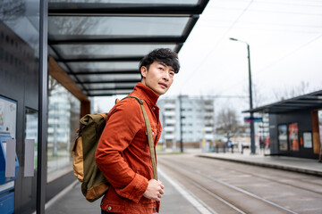 Asian young backpacker waiting the train at platform of metro station. 