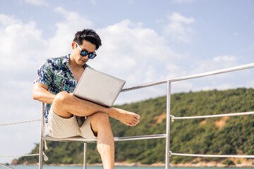 Asian young handsome businessman use laptop computer working in yacht. 