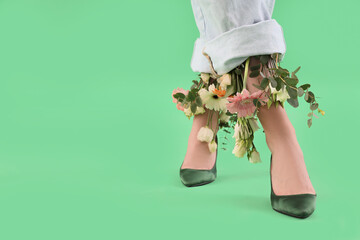 Woman in high heels with flowers on green background, closeup