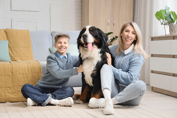 Little boy and his mother with Bernese mountain dog sitting on floor at home