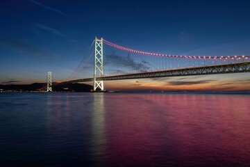ライトアップされた明石海峡大橋と赤く染まる水面のコラボ情景