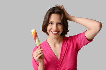 Happy young woman with sweet ice-cream on grey background