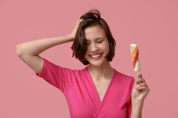 Happy young woman with sweet ice-cream on pink background