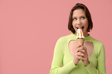 Beautiful young woman eating sweet ice-cream in waffle cone on pink background