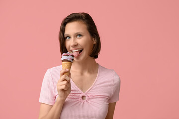 Beautiful young woman eating sweet ice-cream in waffle cone on pink background