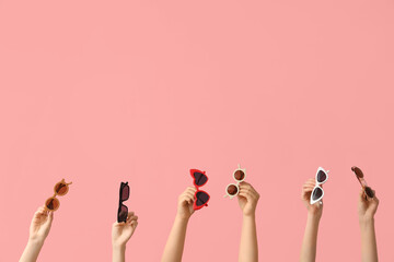 Female hands with different stylish sunglasses on pink background