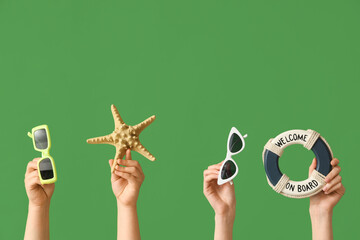 Female hands with stylish sunglasses, mini lifebuoy and starfish on green background