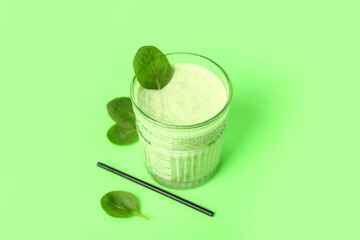 Glass of fresh spinach smoothie on green background