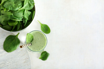 Glass of fresh smoothie and bowl with spinach on white background