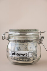 Glass jar full of American currency dollars cash banknote with text RETIREMENT. Preparation saving...