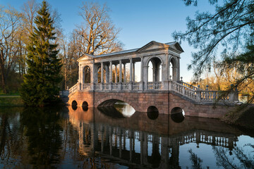 Marble bridge on the shore of a Large pond in the Catherine Park in Tsarskoye Selo on a sunny spring day, Pushkin, St. Petersburg, Russia
