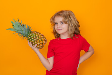 Kid with pineapple in studio. Studio portrait of cute child hold pineapple isolated on yellow background.