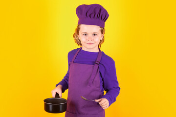 Kid chef cook with cooking pot stockpot. Excited chef cook. Child wearing cooker uniform and chef hat preparing food, studio portrait.