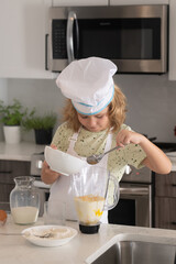 Kid chef cook cookery at kitchen. Cooking, culinary and kids. Little boy in chefs hat and apron.