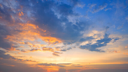 Dramatic sunset horizon sky with orange sunlight and dark clouds on blue idyllic dusk sky background in evening time