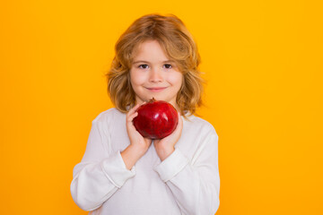 Pomegranate. Kid hold red pomegranate in studio. Pomegranate fruit. Studio portrait of cute child with pomegranate isolated on yellow background.
