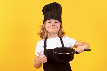 Funny kid chef cook with kitchen pot stockpot. Child chef cook. Child wearing cooker uniform and chef hat preparing food, studio portrait.