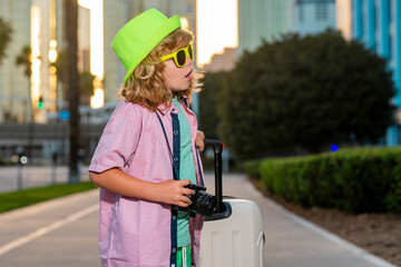 Child with travel suitcase on vacation. Kids travel and adventure concept. Child boy going on vacation holding luggage travel bag outdoor.