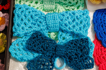 A table with a variety of knitted items, including a blue and green bow