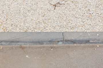 A grey concrete curb with white gravel border