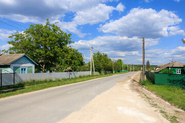 A rural road with a few houses and trees in the background