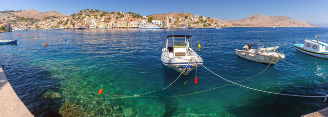 Panoramic harbor view with traditional fishing boat on Symi Island, Greece
