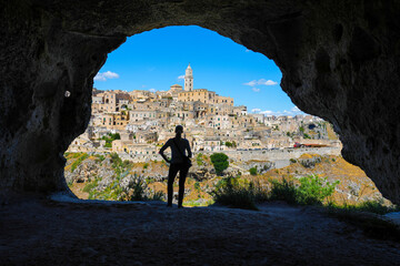 Woman enjoying view of Matera from cave across canyon