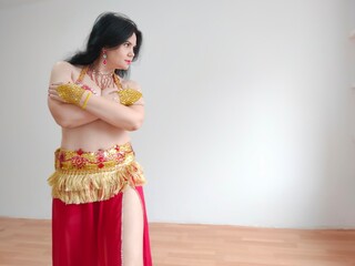 A dancer in a red suit is dancing an oriental dance on a white background. Free space for text....