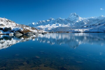 Obraz premium A pristine mountain lake reflecting snow-capped peaks under a clear blue sky